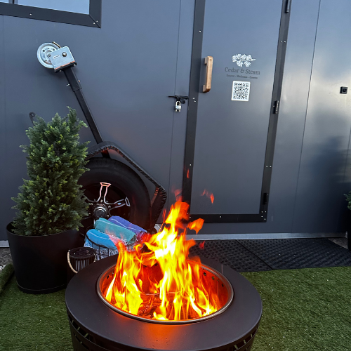 Wood-fired sauna setup at The Denver Village with a roaring fire pit in front